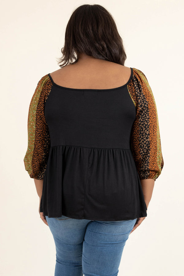 Plus Size black babydoll top with floral striped balloon sleeves and distressed blue jeans.