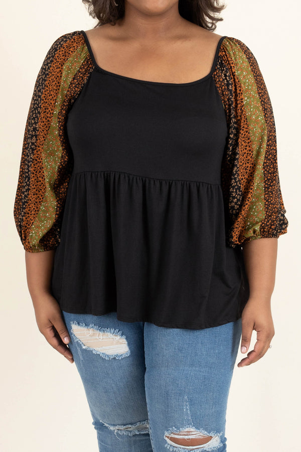 Plus Size black babydoll top with floral striped balloon sleeves and distressed blue jeans.