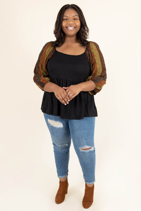 Plus Size black babydoll top with floral striped balloon sleeves and distressed blue jeans.