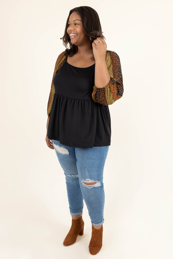 Plus Size black babydoll top with floral striped balloon sleeves and distressed blue jeans.