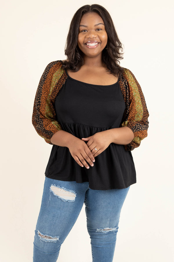Plus Size black babydoll top with floral striped balloon sleeves and distressed blue jeans.