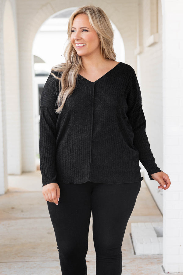 Plus Size black shimmery V-neck sweater with long sleeves and exposed seam detailing.